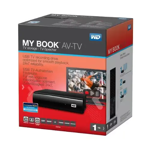 Disque dur externe Western Digital 1To My Book AV-TV noir posé sur un meuble TV, avec une télévision en arrière-plan.